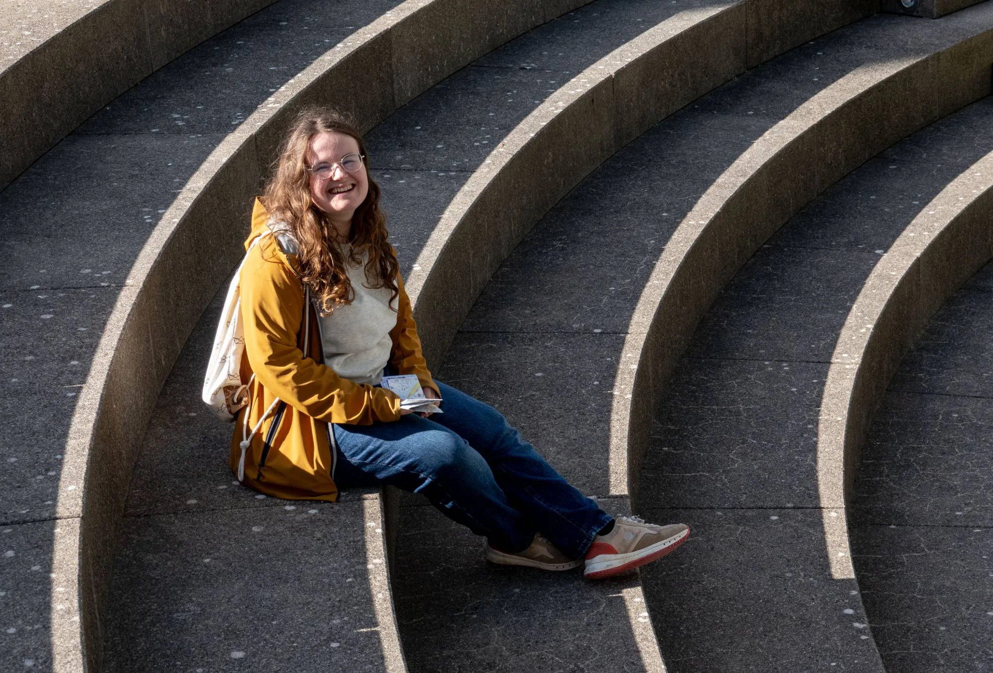Karin Hugentobler laughing, sitting on curved concrete steps in the sun